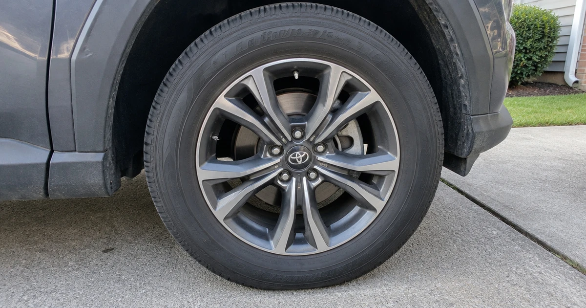 All Season Tires mounted on a parked car in a sunlit driveway