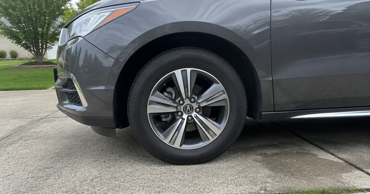 A tire for Acura MDX mounted on an SUV in a residential driveway