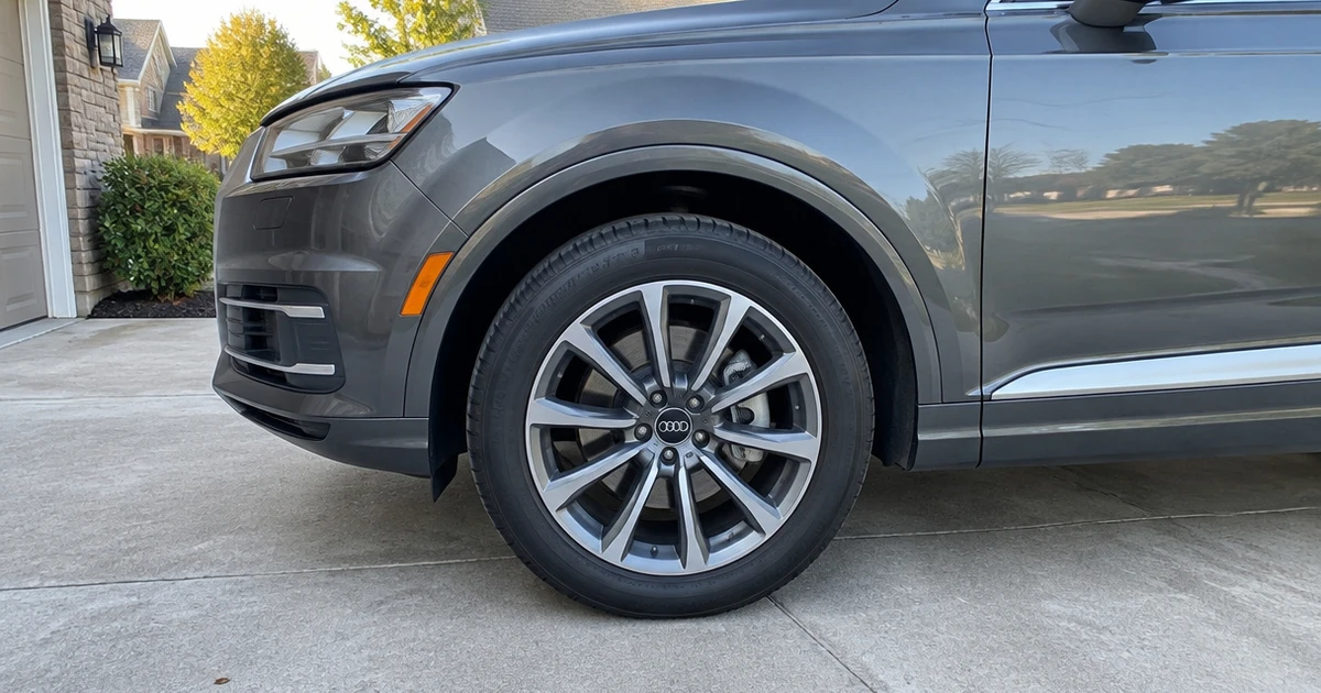 A tire for Audi Q7 sits fitted to the SUV on a quiet residential driveway