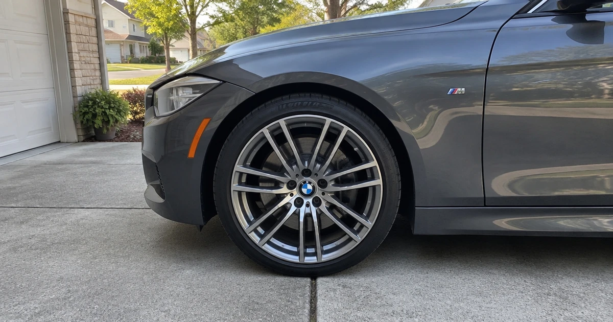 A BMW 3 Series parked curbside with tires for BMW 3 Series visible on its wheels