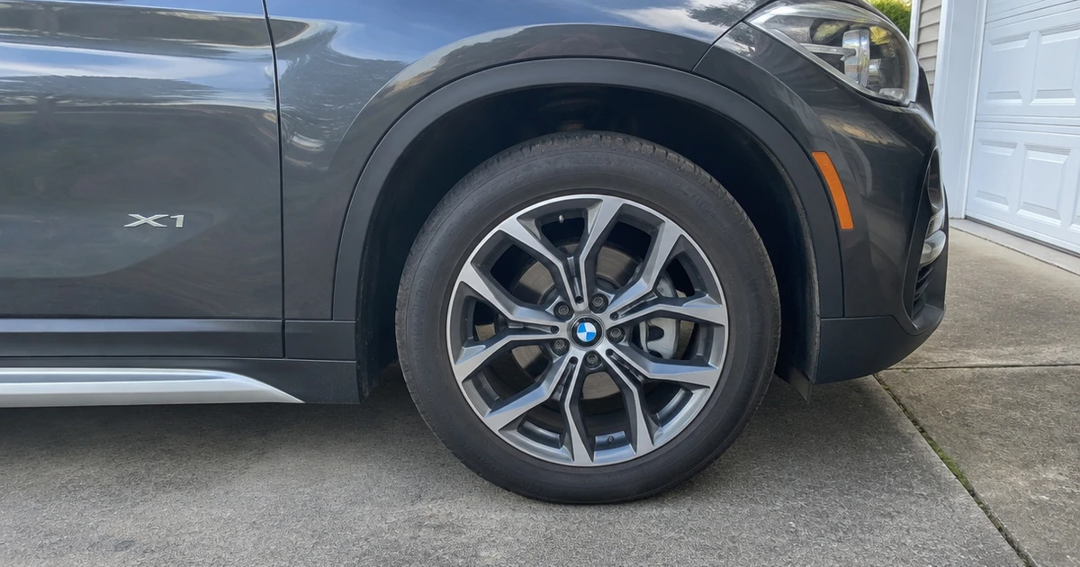 A BMW X1 with a fitted tire shows tires for BMW X1 in a driveway