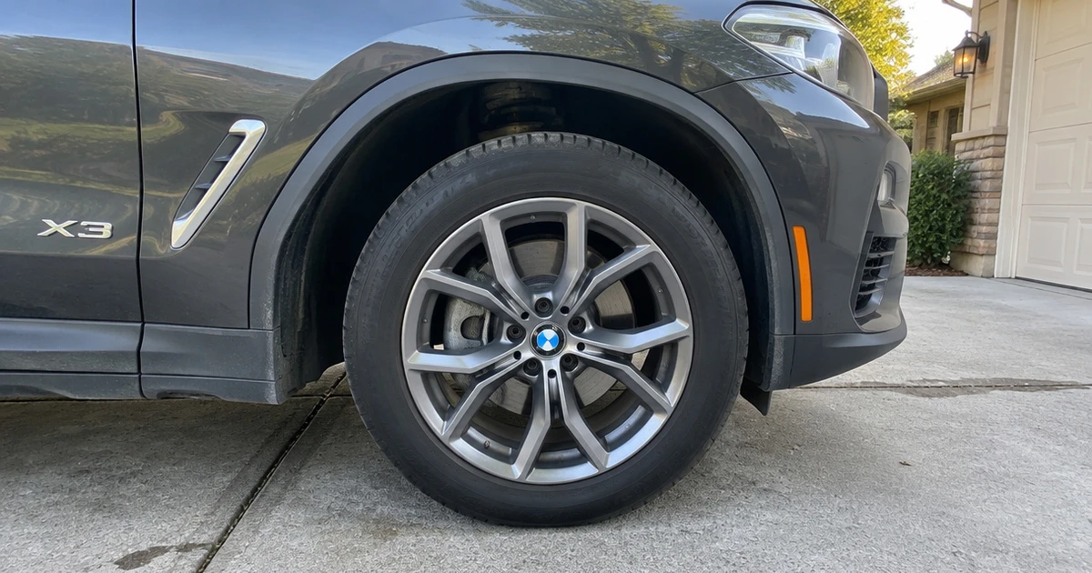 A BMW X3 parked in a driveway shows tires for BMW X3 in sharp focus