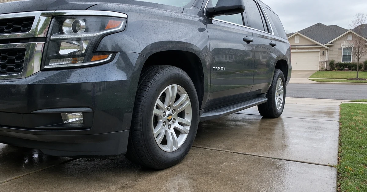 Tires for Chevy Tahoe on a parked SUV in a residential driveway after rain