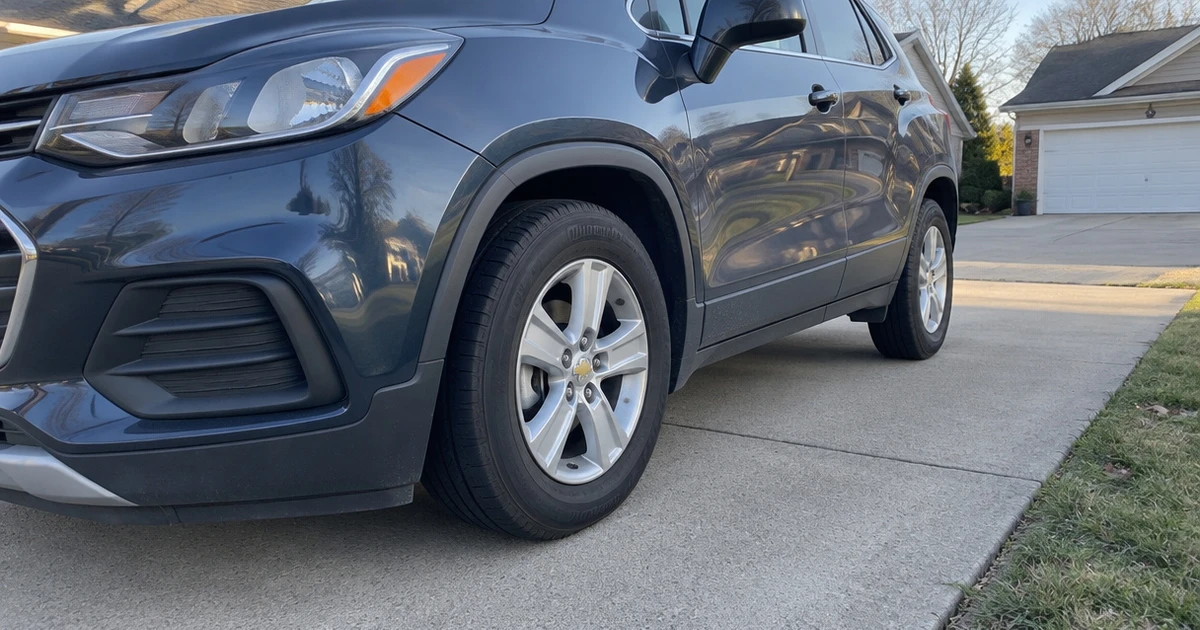 Tires for Chevy Trax sit mounted on a parked SUV in a sunlit driveway