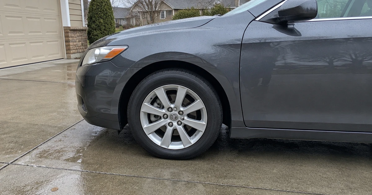 Tires for Comfort and Noise sit on a parked sedan in a quiet driveway