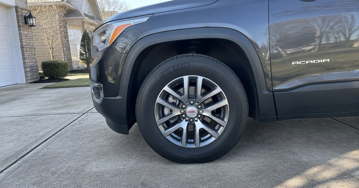 A GMC Acadia sits on a neighborhood street, showing tires for GMC Acadia clearly