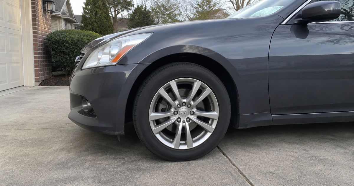 A tire for Infiniti G37 mounted on a sedan parked in a sunlit driveway