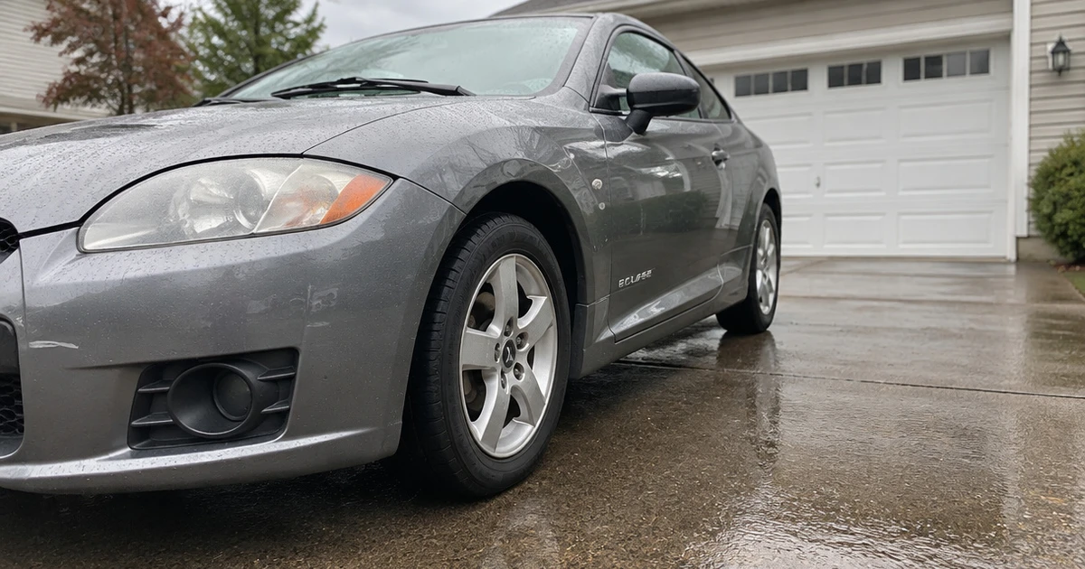 A parked Mitsubishi Eclipse shows tires for Mitsubishi Eclipse on a quiet driveway