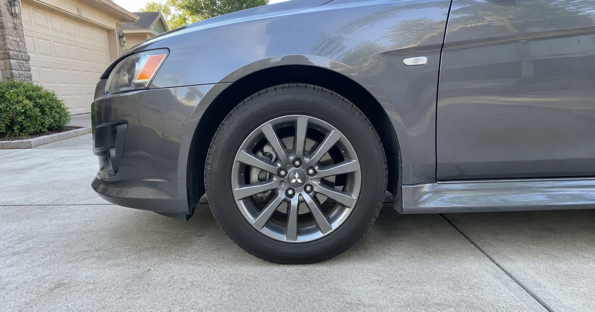 A close view shows tires for Mitsubishi Lancer fitted to a parked sedan