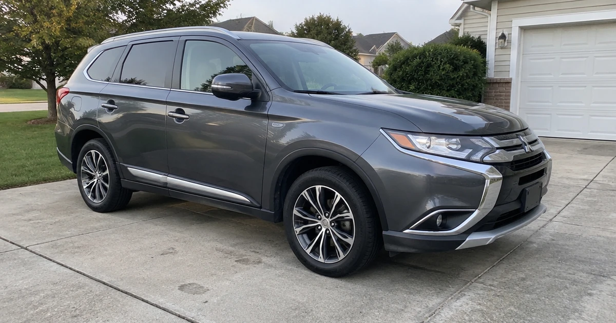 A tire for Mitsubishi Outlander appears on the front wheel of a parked SUV