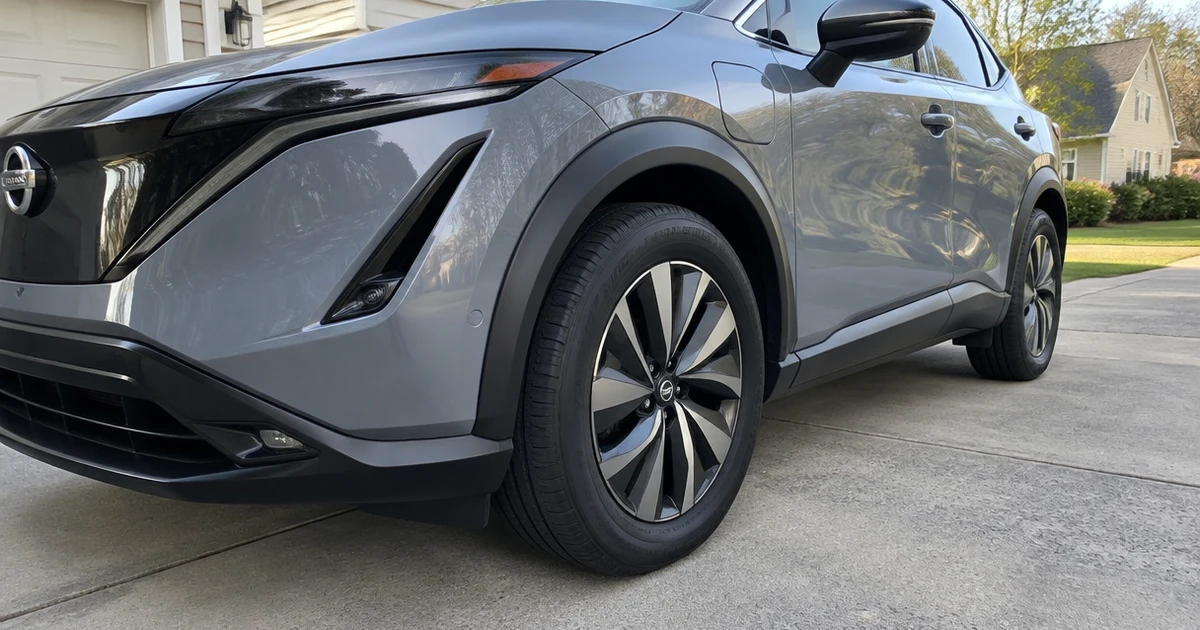 Tires for Nissan Ariya appear on a parked electric SUV in a sunlit driveway