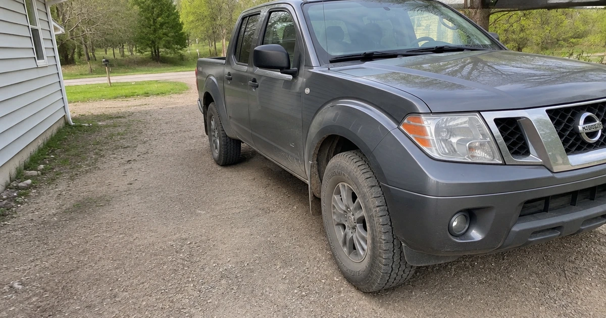 A Nissan Frontier parked beside a trail shows tires for Nissan Frontier in natural light