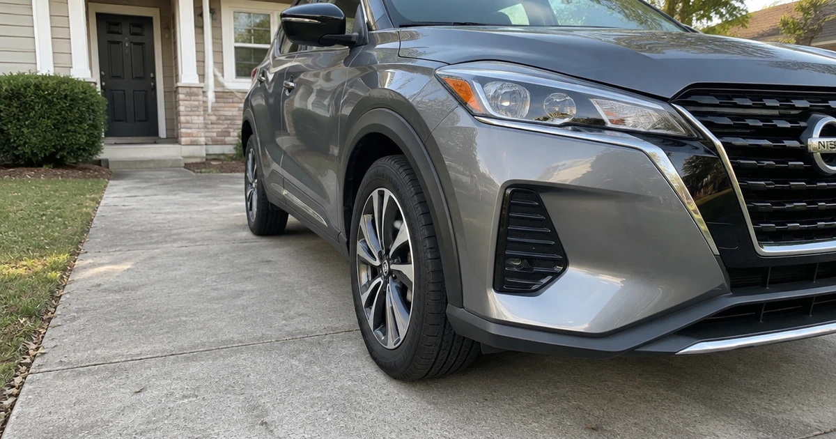 A Nissan Kicks sits in daylight on a driveway with tires for Nissan Kicks visible