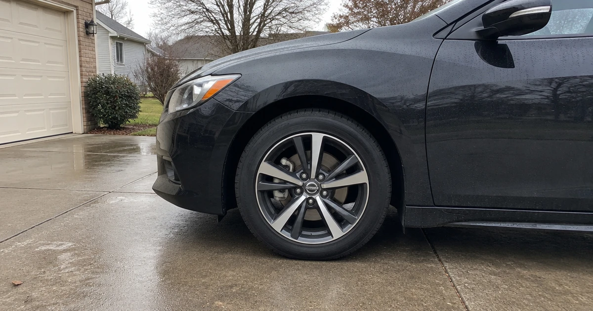 A Nissan Maxima sits in a driveway with tires for Nissan Maxima fitted