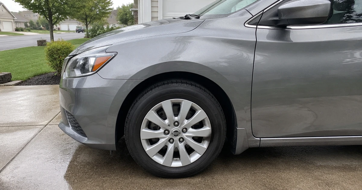 A Nissan Sentra parked on a driveway with tires for Nissan Sentra fitted and visible