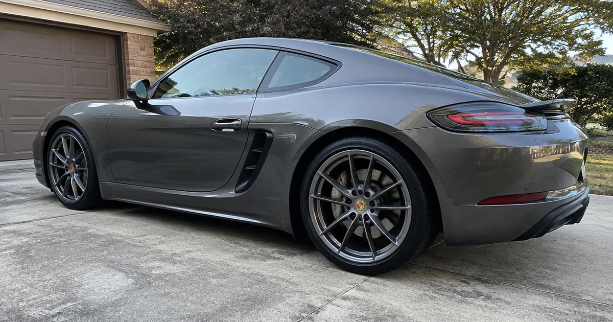 A tire for Porsche 718 is fitted to a parked car in a driveway