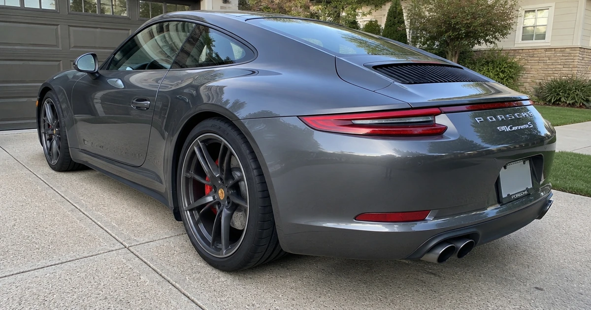 A Porsche 911 on a driveway, with tires for Porsche 911 visible at the rear