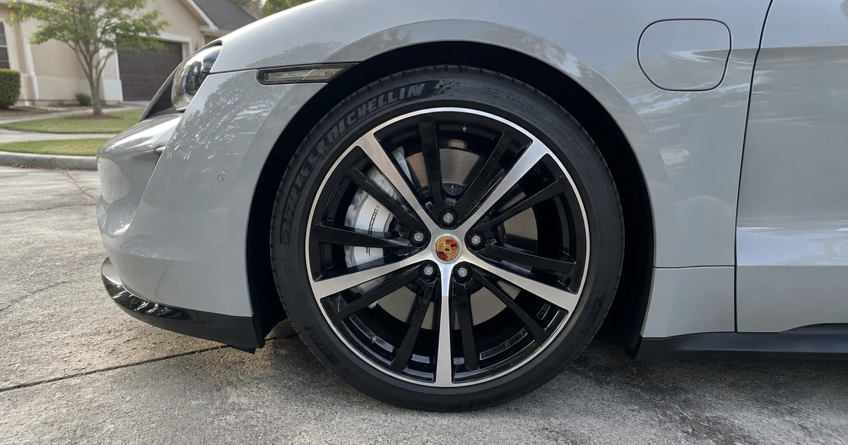 A tire for Porsche Taycan mounted on the car in a sunlit driveway