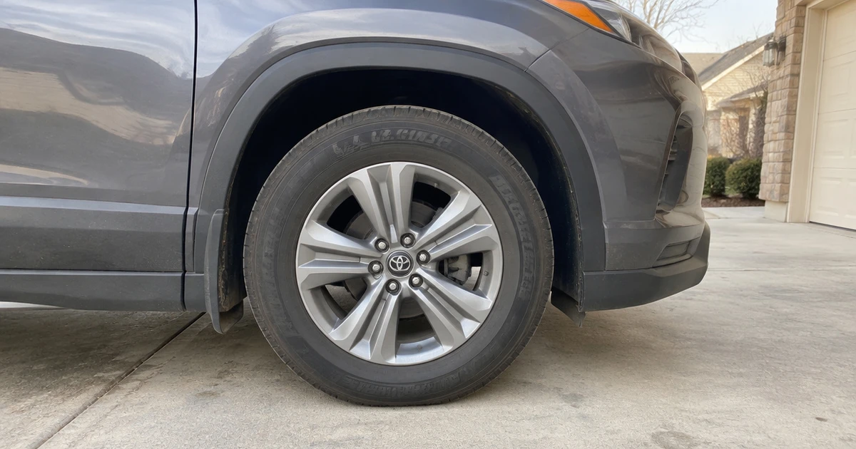 Tires for SUVs grip a family crossover parked on a sunlit neighborhood street
