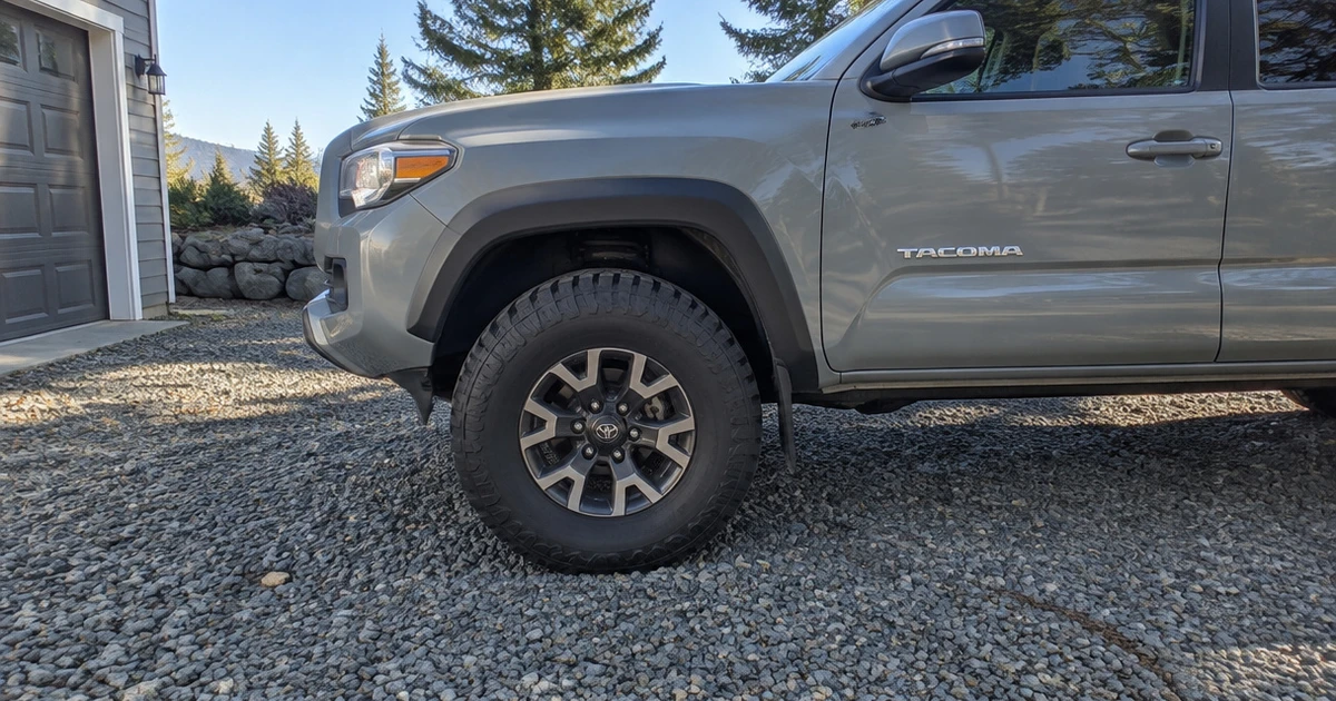 A Tacoma parked on a gravel drive with tires for Toyota Tacoma fitted and visible